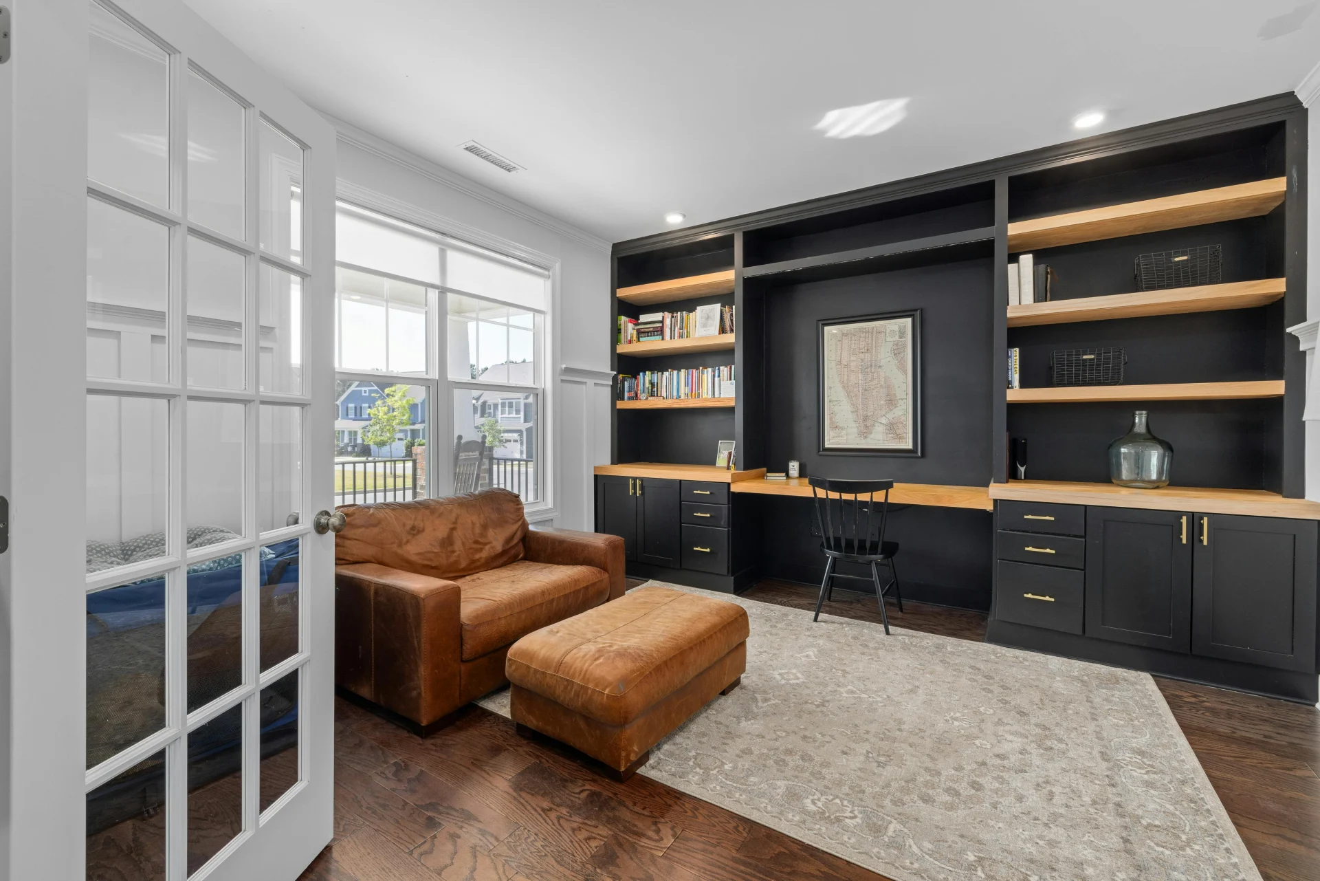 home office with dark gray built in desk, shelves, and cabinets