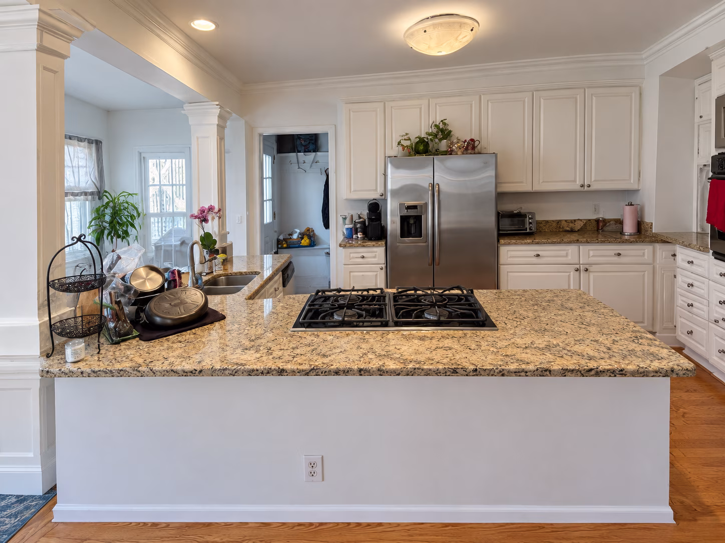 Original kitchen before remodeling, with white cabinetry, raised cooktop counter and decorative columns.